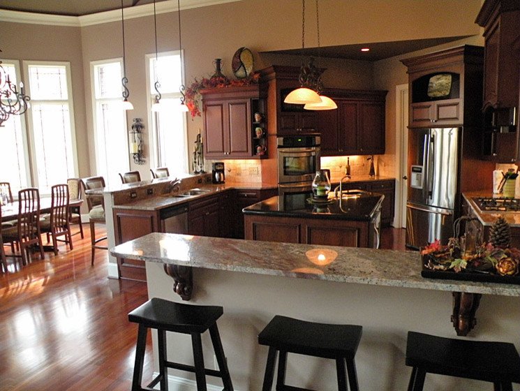 Example of a mid-sized transitional u-shaped medium tone wood floor open concept kitchen design in Charlotte with recessed-panel cabinets, dark wood cabinets, marble countertops, beige backsplash, an island, a double-bowl sink, porcelain backsplash and stainless steel appliances