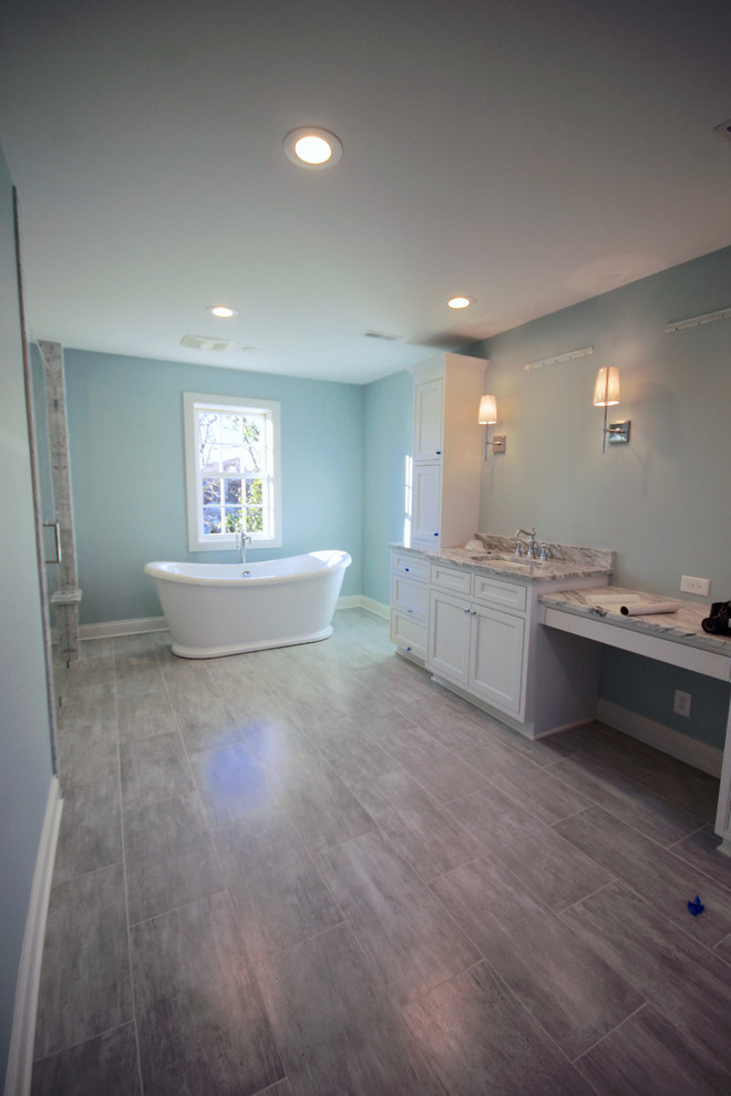 Photo of a large transitional master bathroom in Cincinnati with recessed-panel cabinets, white cabinets, a freestanding tub, a corner shower, blue walls, laminate floors, an undermount sink, quartzite benchtops, grey floor, an open shower and grey benchtops.