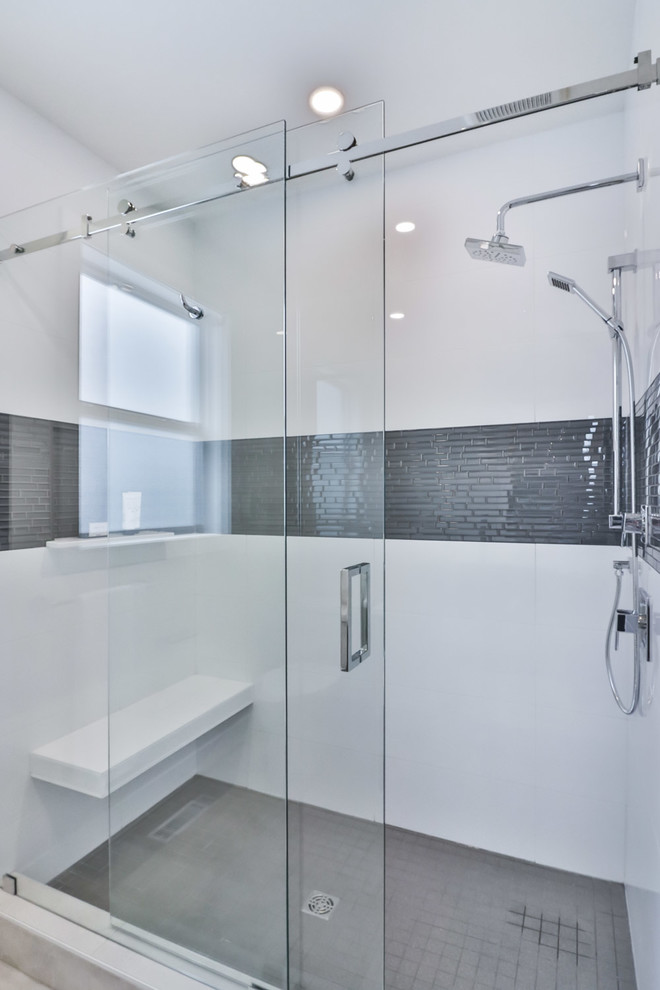 Example of a large transitional master white tile and porcelain tile porcelain tile and gray floor drop-in bathtub design with flat-panel cabinets, gray cabinets, a one-piece toilet, gray walls, an undermount sink and quartz countertops