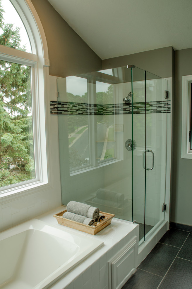 This is an example of a large transitional master bathroom in Minneapolis with flat-panel cabinets, white cabinets, a drop-in tub, an open shower, gray tile, ceramic tile, grey walls, ceramic floors, a drop-in sink, granite benchtops, grey floor and a hinged shower door.