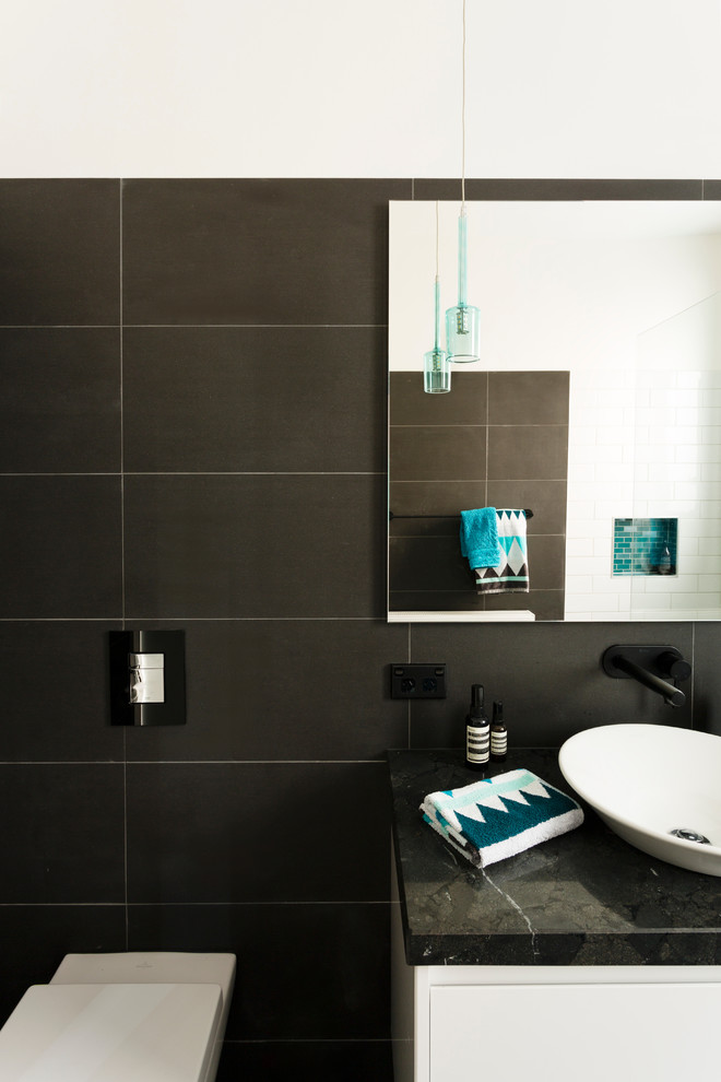 Mid-sized arts and crafts master bathroom in Melbourne with flat-panel cabinets, white cabinets, a wall-mount toilet, black tile, ceramic tile, black walls and granite benchtops.