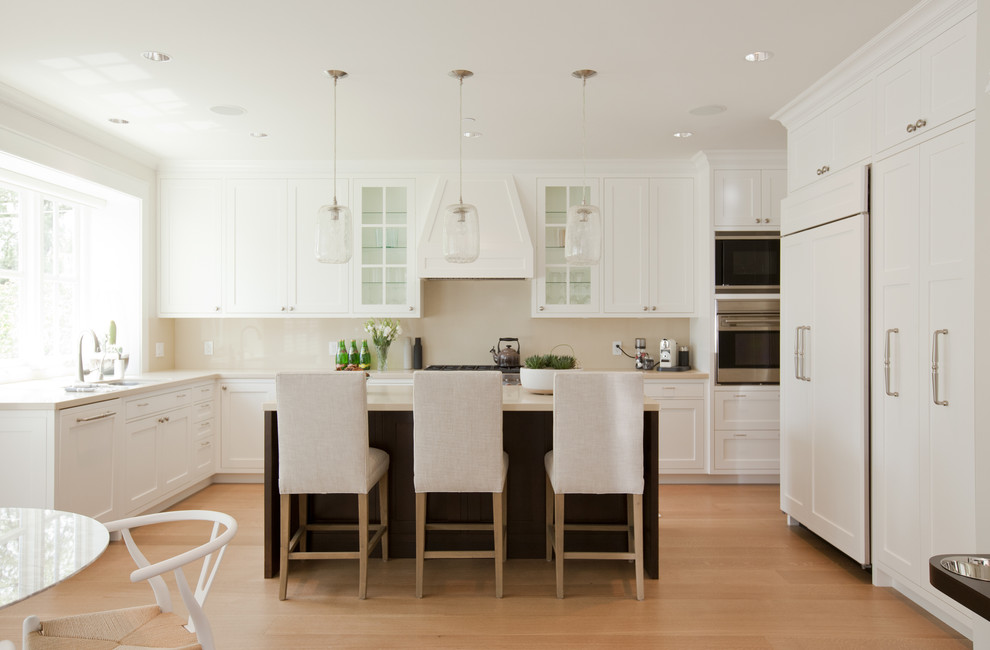 Photo of a traditional u-shaped eat-in kitchen in Vancouver with an undermount sink, shaker cabinets, white cabinets, quartz benchtops, stone slab splashback and panelled appliances.