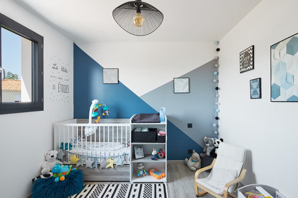 Inspiration for a mid-sized scandinavian gender-neutral nursery in Nantes with blue walls, laminate floors and grey floor.