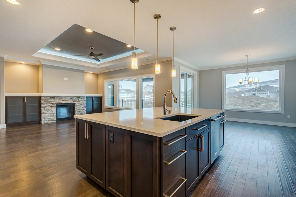 Example of a mid-sized transitional l-shaped medium tone wood floor open concept kitchen design in Seattle with an undermount sink, shaker cabinets, white cabinets, quartz countertops, gray backsplash, stone tile backsplash, stainless steel appliances and an island