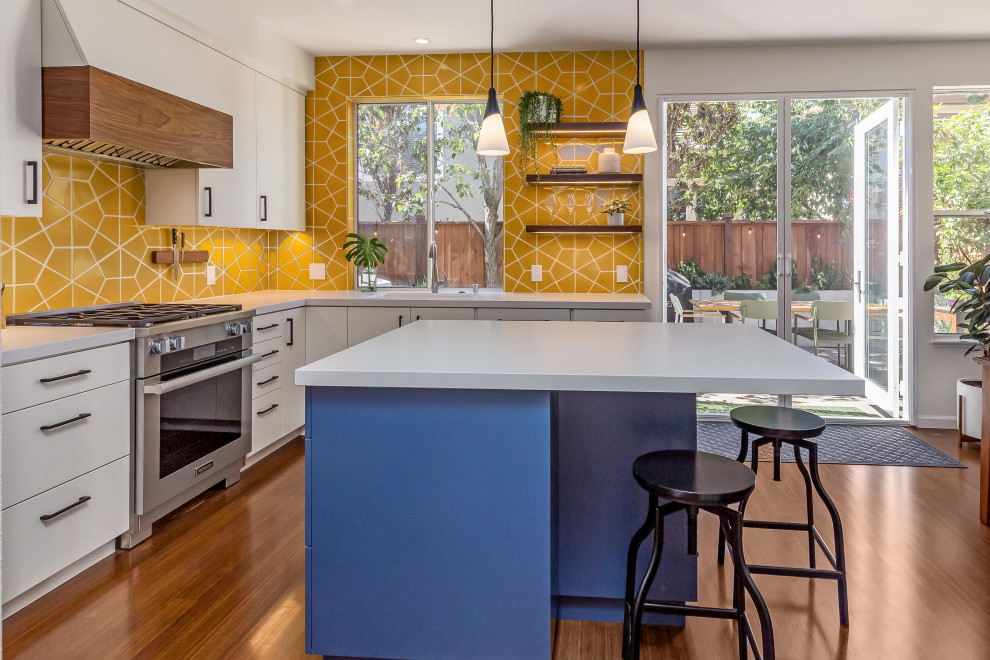 Inspiration for a medium sized midcentury u-shaped kitchen/diner in San Francisco with a submerged sink, flat-panel cabinets, white cabinets, engineered stone countertops, yellow splashback, ceramic splashback, stainless steel appliances, medium hardwood flooring, an island, brown floors, white worktops and a timber clad ceiling.