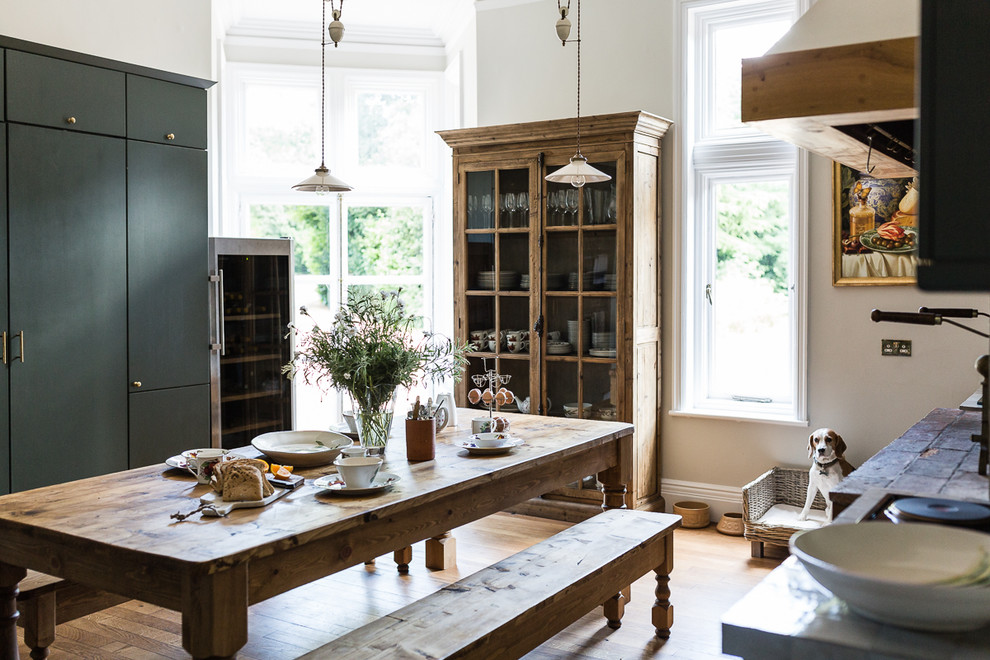 This is an example of a large country kitchen/dining combo in Cambridgeshire with medium hardwood floors and beige walls.