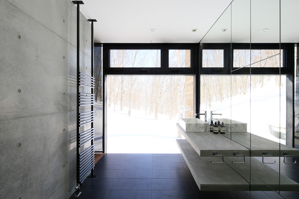 Example of an urban black floor powder room design in Other with concrete countertops, open cabinets, gray cabinets, gray walls and a vessel sink