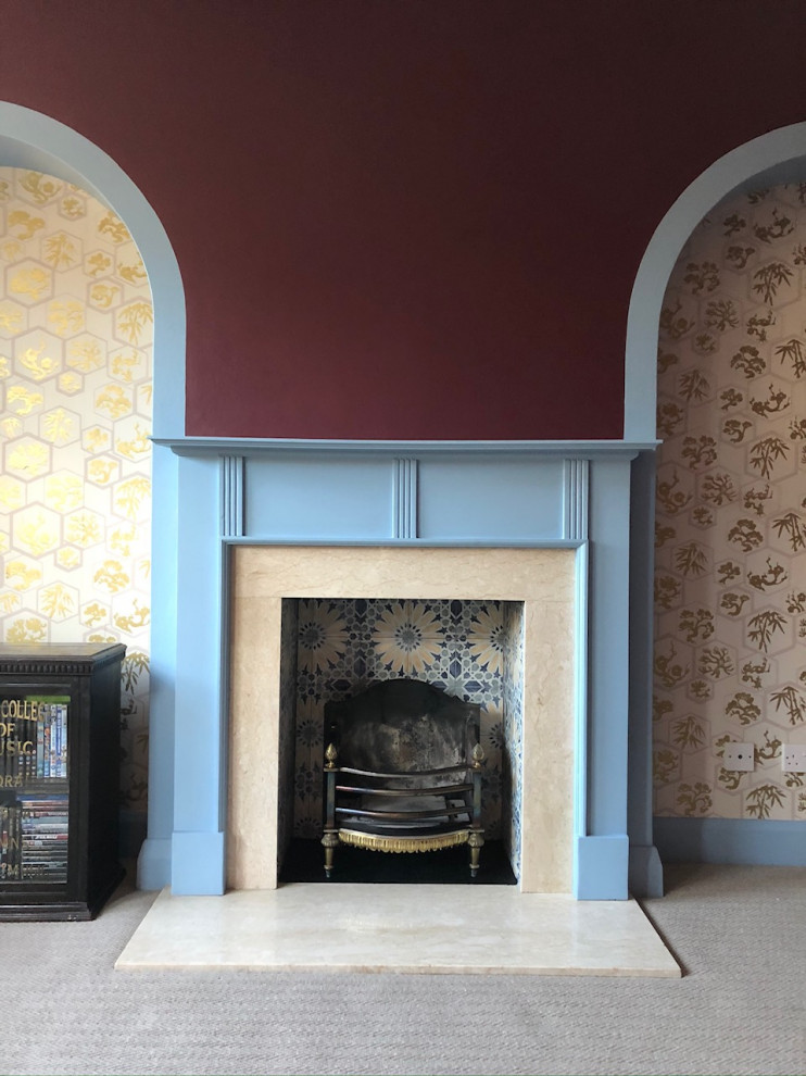 Inspiration for a small bohemian formal enclosed living room in London with red walls, carpet, a standard fireplace, a wooden fireplace surround, a freestanding tv, grey floors and wallpapered walls.