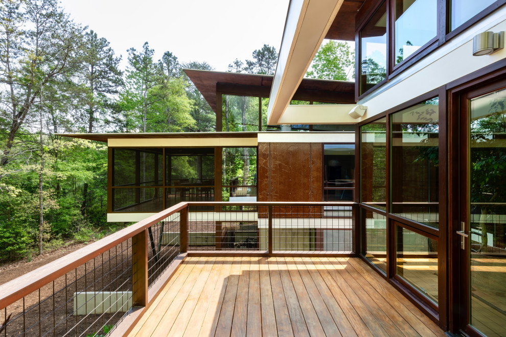 Modelo de terraza planta baja minimalista de tamaño medio sin cubierta en patio trasero con barandilla de metal