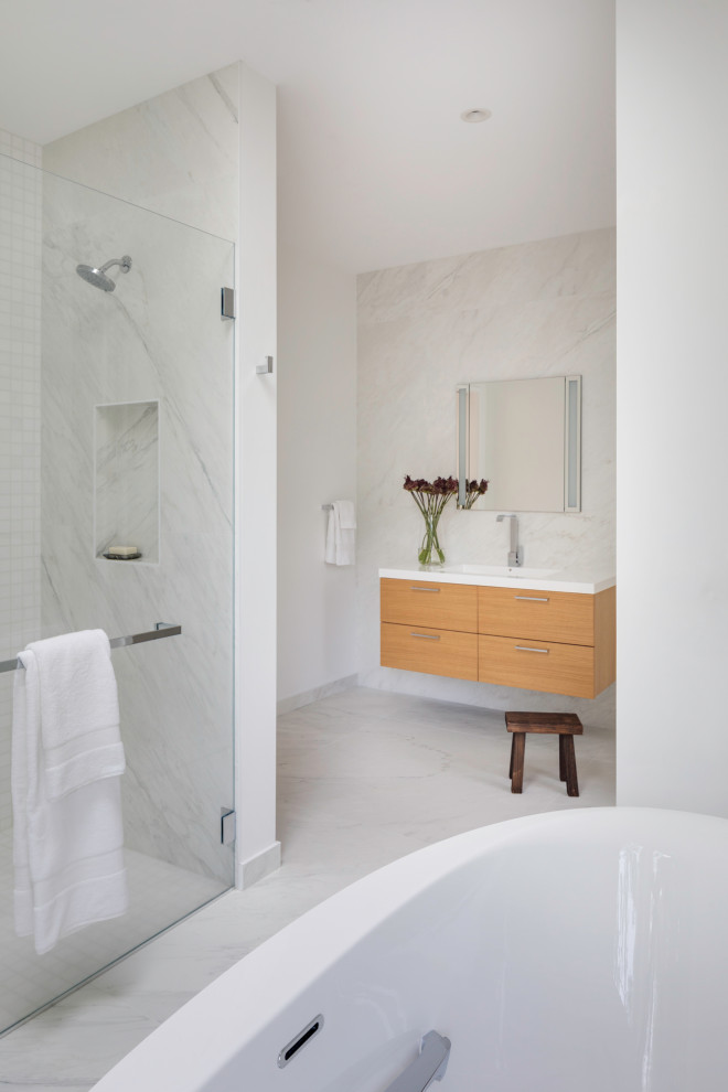 Inspiration for a mid-sized contemporary master bathroom in Boston with flat-panel cabinets, light wood cabinets, an alcove tub, ceramic tile, an integrated sink, engineered quartz benchtops, a single vanity, a floating vanity, white tile, white walls, plywood floors, white floor, a hinged shower door and an enclosed toilet.