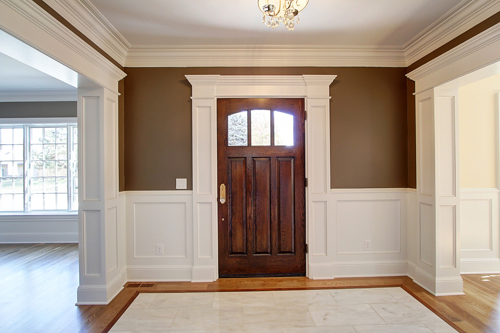 Design ideas for a large transitional foyer in Denver with brown walls, marble floors, a single front door, a dark wood front door and white floor.