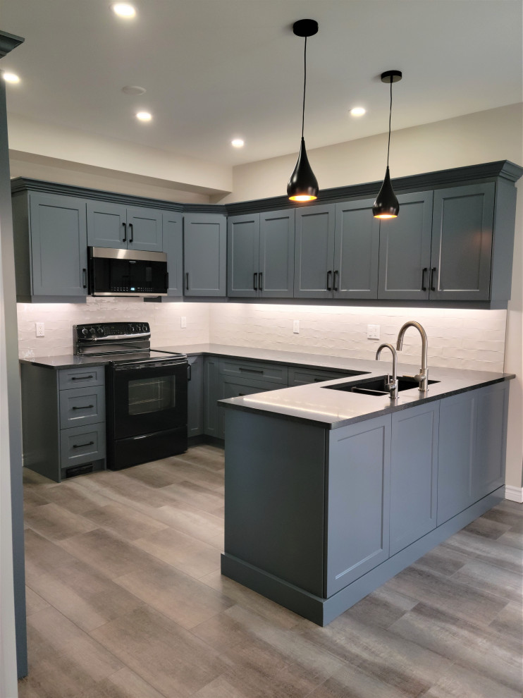 Mid-sized transitional u-shaped vinyl floor eat-in kitchen photo with an undermount sink, recessed-panel cabinets, blue cabinets, quartzite countertops, white backsplash, porcelain backsplash, black appliances, a peninsula and black countertops
