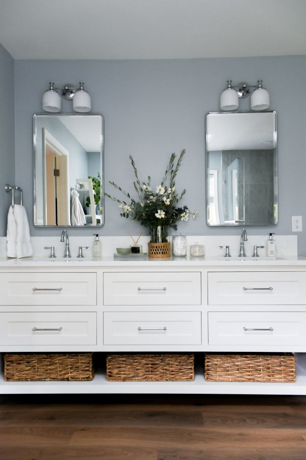 Example of a transitional master multicolored tile vinyl floor, brown floor and double-sink corner shower design with shaker cabinets, white cabinets, blue walls, an undermount sink, quartz countertops, a hinged shower door, white countertops and a built-in vanity