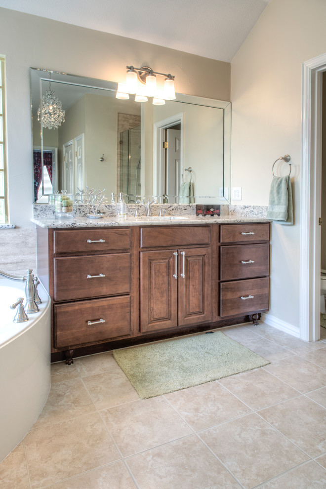 Inspiration for a large contemporary master bathroom in Dallas with an undermount sink, furniture-like cabinets, brown cabinets, granite benchtops, an alcove shower, beige tile, ceramic tile, ceramic floors and beige floor.