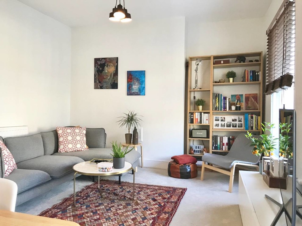 This is an example of a small scandinavian enclosed living room in London with white walls, concrete floors, a freestanding tv and grey floor.