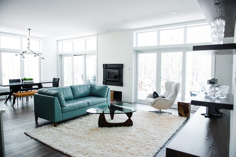 Inspiration for a large modern open concept living room in Other with white walls, dark hardwood floors, a standard fireplace, a metal fireplace surround, brown floor and a freestanding tv.