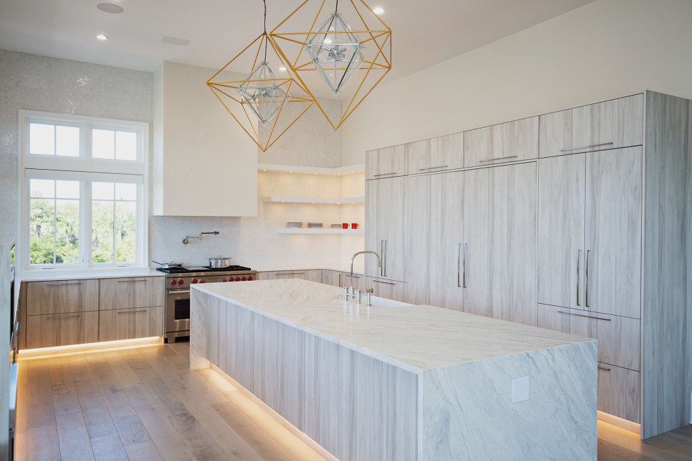 This is an example of an expansive beach style u-shaped eat-in kitchen in Miami with a farmhouse sink, flat-panel cabinets, light wood cabinets, quartzite benchtops, white splashback, porcelain splashback, panelled appliances, light hardwood floors, with island, beige floor and white benchtop.