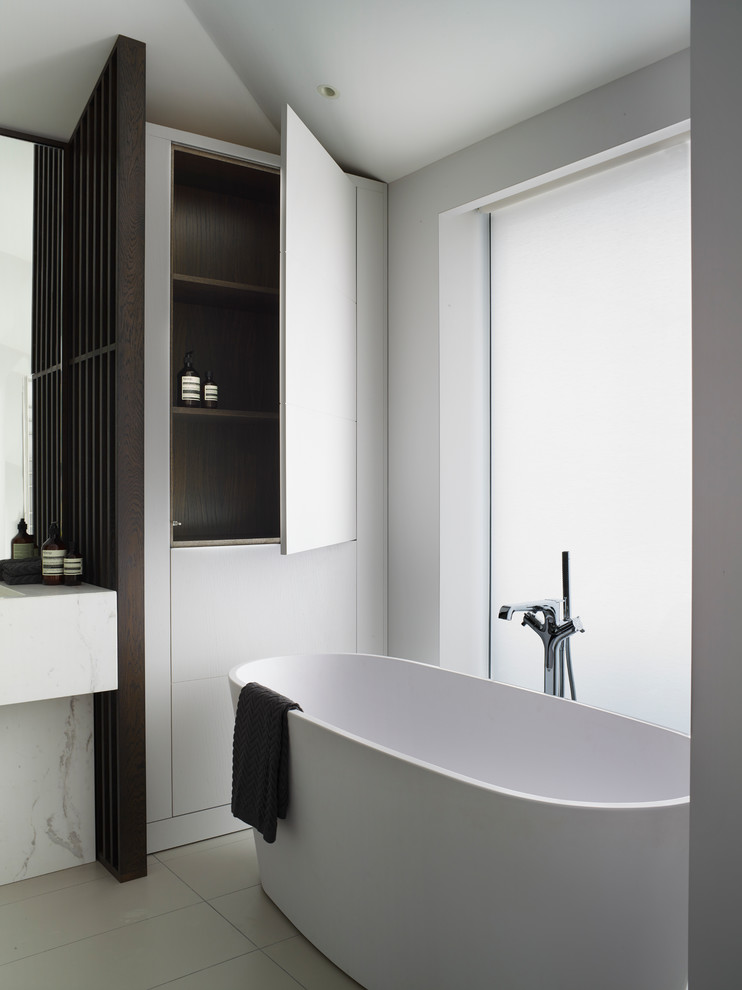 This is an example of a large contemporary master bathroom in London with flat-panel cabinets, blue cabinets, a wall-mount toilet, marble, yellow walls, marble benchtops, grey floor and white benchtops.