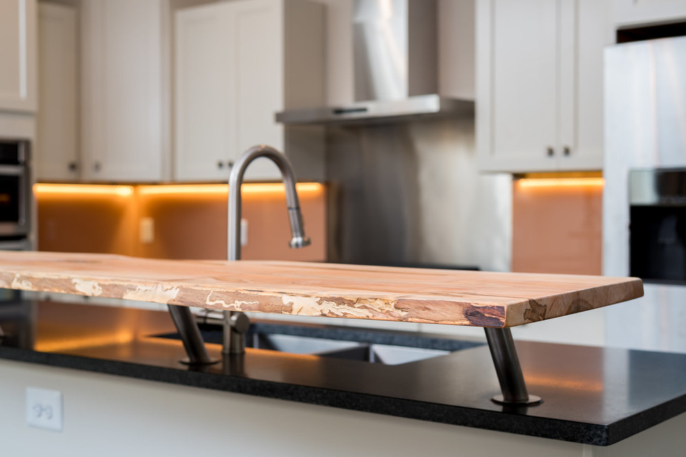 Example of a transitional u-shaped eat-in kitchen design in DC Metro with a double-bowl sink, shaker cabinets, white cabinets, granite countertops, brown backsplash, glass sheet backsplash, stainless steel appliances, an island and black countertops
