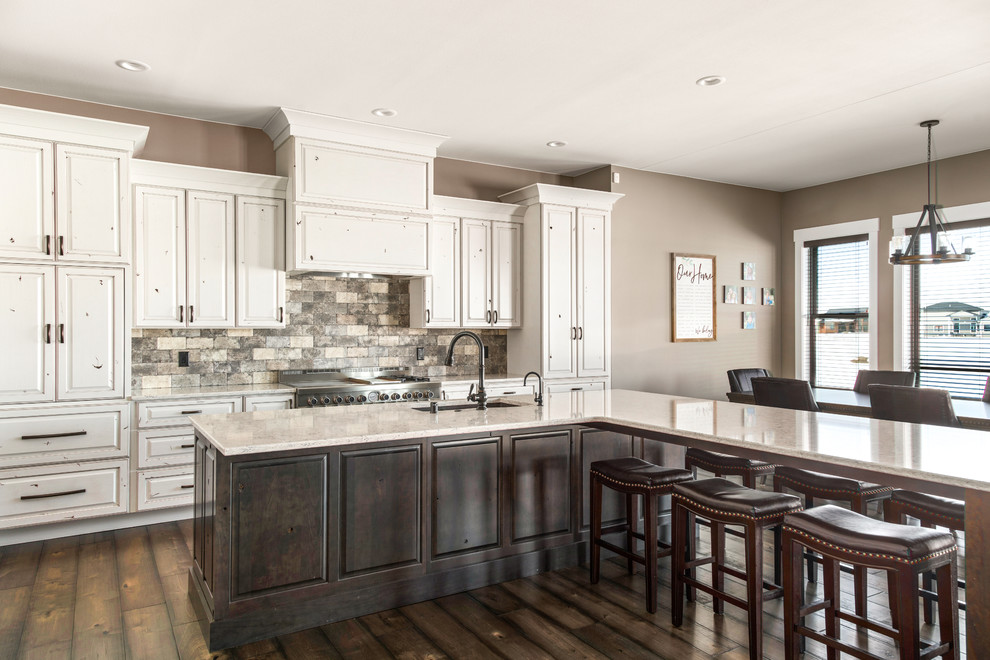 Eat-in kitchen - large transitional l-shaped medium tone wood floor and brown floor eat-in kitchen idea with an undermount sink, raised-panel cabinets, quartz countertops, beige backsplash, stone tile backsplash, stainless steel appliances, an island and beige countertops