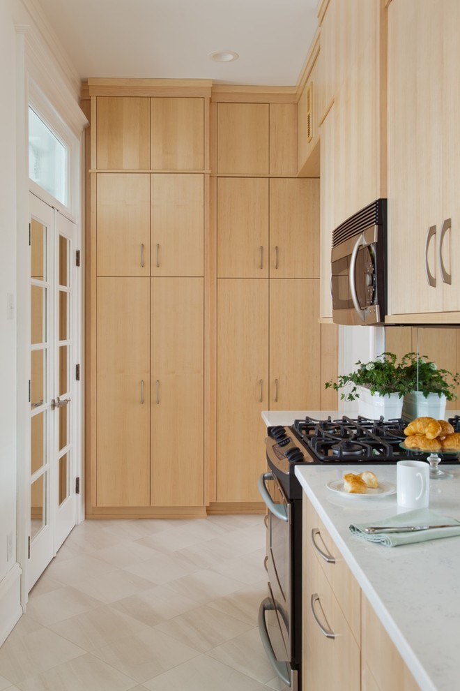 Photo of a small modern galley separate kitchen in Richmond with an undermount sink, flat-panel cabinets, light wood cabinets, quartz benchtops, stainless steel appliances, ceramic floors, no island and mirror splashback.