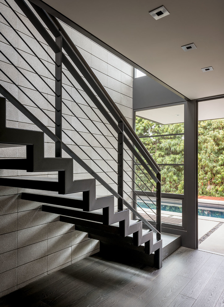This is an example of a midcentury floating staircase in Orange County with open risers and cable railing.