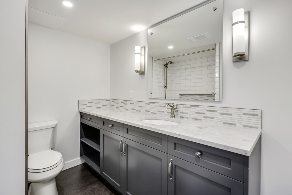 Photo of a small transitional master bathroom in Calgary with shaker cabinets, brown cabinets, a drop-in tub, a shower/bathtub combo, a two-piece toilet, multi-coloured tile, mosaic tile, grey walls, cork floors, an undermount sink, quartzite benchtops, brown floor, a shower curtain and white benchtops.