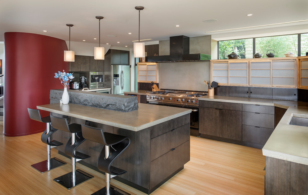 Photo of an asian l-shaped open plan kitchen in Seattle with a single-bowl sink, flat-panel cabinets, dark wood cabinets, concrete benchtops, grey splashback, stainless steel appliances, bamboo floors and with island.