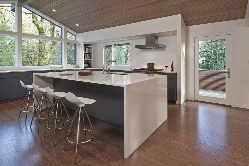 Photo of a contemporary l-shaped kitchen in Seattle with an undermount sink, flat-panel cabinets, grey cabinets, white splashback, medium hardwood floors and with island.