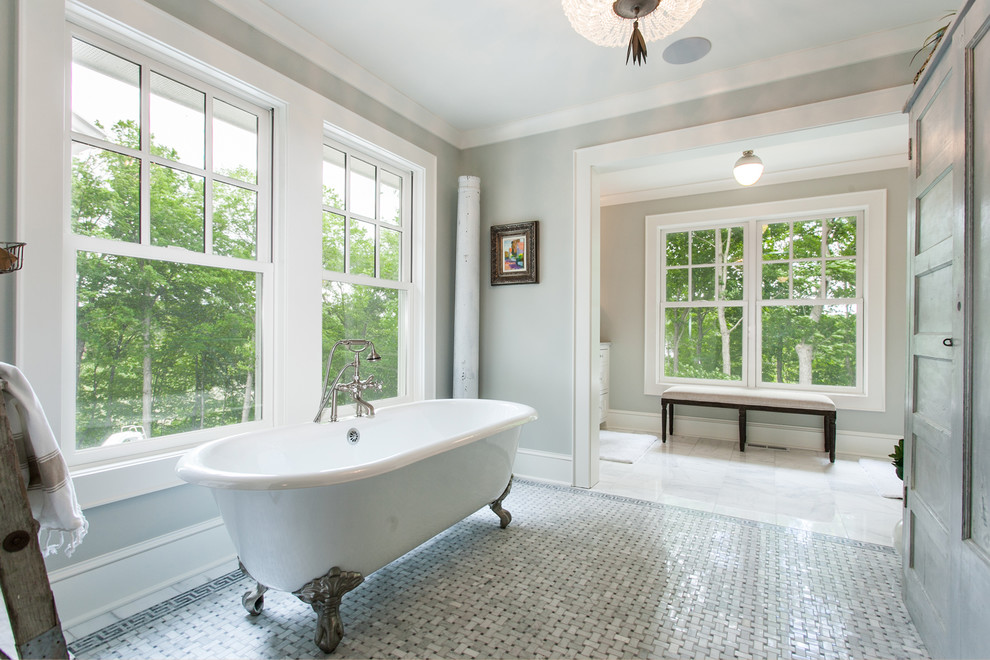 Eclectic master bathroom with a claw-foot tub, grey walls and grey floor.