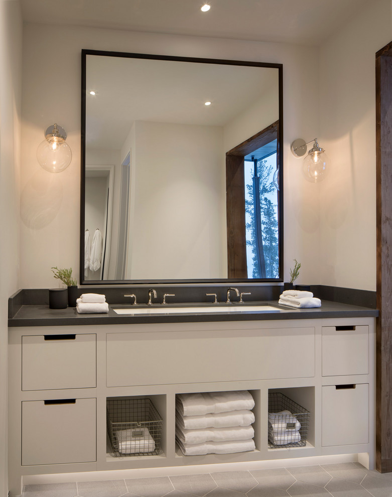 Modern Ski Home - Example of a mountain style gray floor freestanding bathtub design with flat-panel cabinets, white cabinets, a trough sink and black countertops