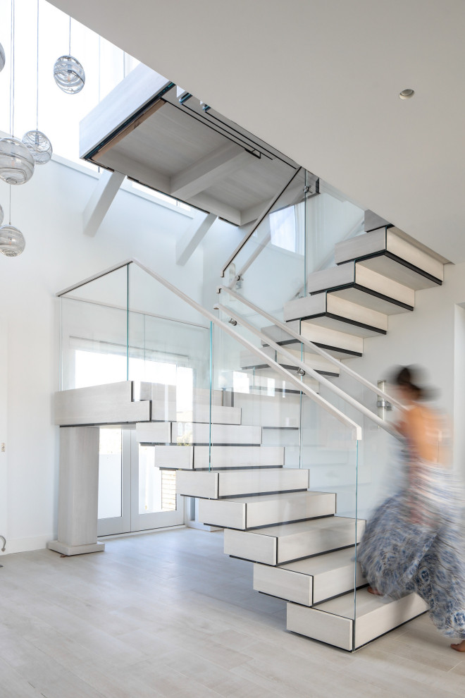 Cette photo montre un escalier moderne en U avec des marches en bois, des contremarches en bois et un garde-corps en verre.