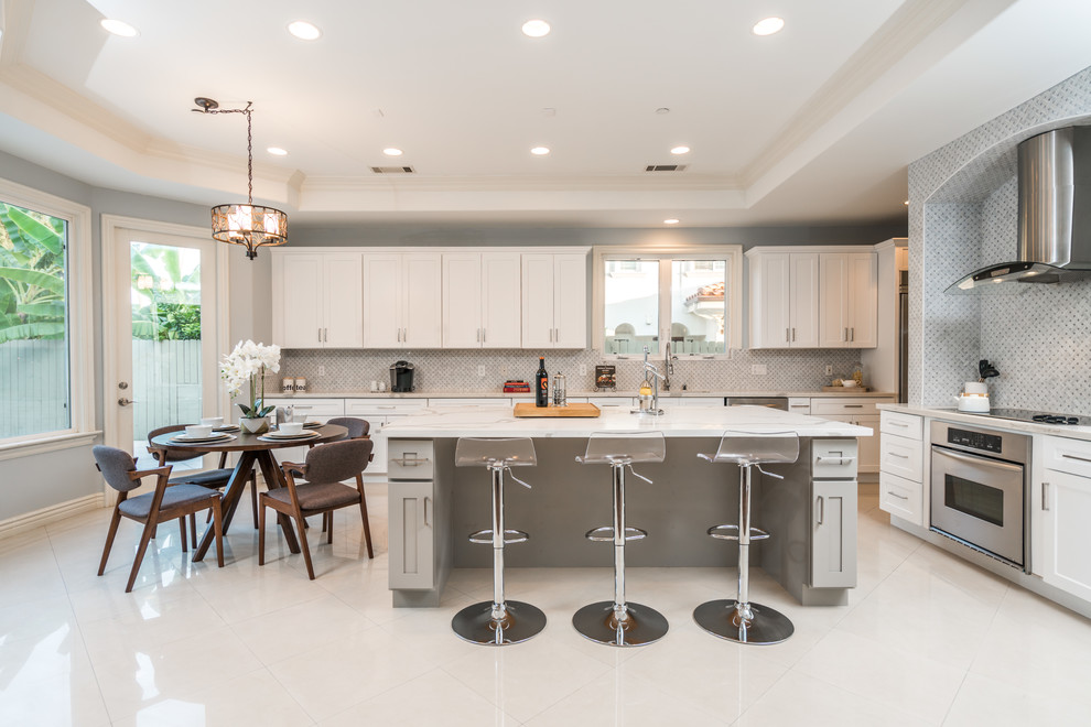 Transitional kitchen in Los Angeles with an undermount sink, shaker cabinets, white cabinets, quartz benchtops, grey splashback, marble splashback, stainless steel appliances, marble floors, with island and white floor.