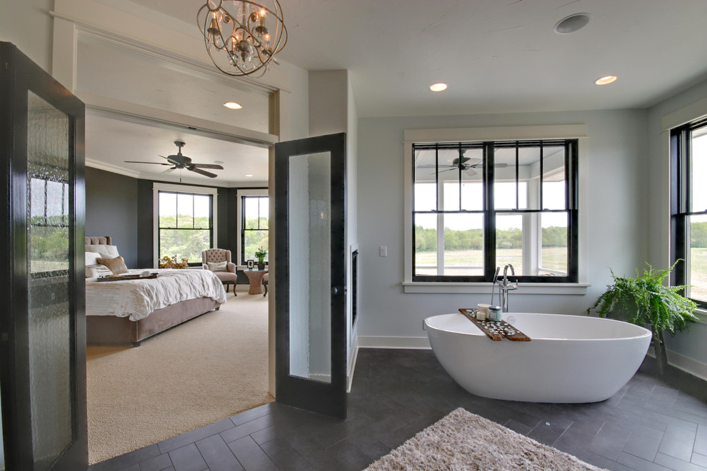 Country master bathroom in Grand Rapids with a freestanding tub, white walls, ceramic floors and gray tile.