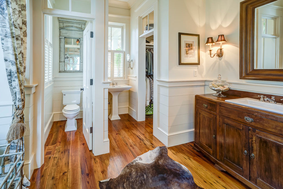 This is an example of a traditional bathroom in Atlanta with a drop-in sink, shaker cabinets, dark wood cabinets, a two-piece toilet, white walls, medium hardwood floors and an enclosed toilet.