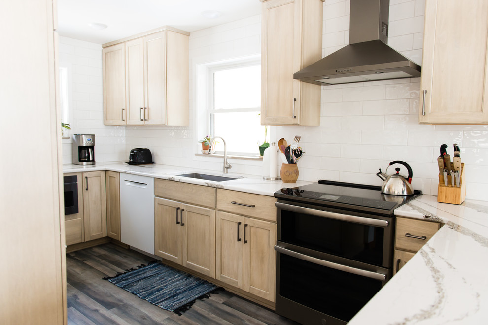 Enclosed kitchen - mid-sized transitional u-shaped vinyl floor and brown floor enclosed kitchen idea with an undermount sink, flat-panel cabinets, beige cabinets, quartz countertops, white backsplash, subway tile backsplash, black appliances, a peninsula and white countertops