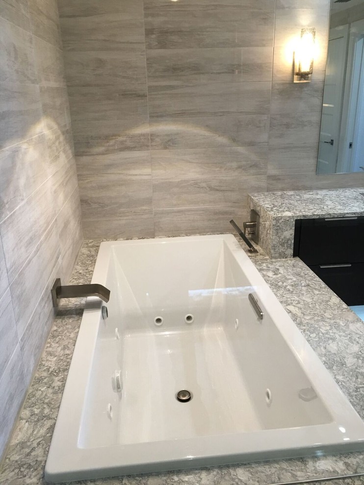 This is an example of a large contemporary master bathroom in Orlando with flat-panel cabinets, dark wood cabinets, a drop-in tub, a double shower, white tile, porcelain tile, porcelain floors, an undermount sink and engineered quartz benchtops.