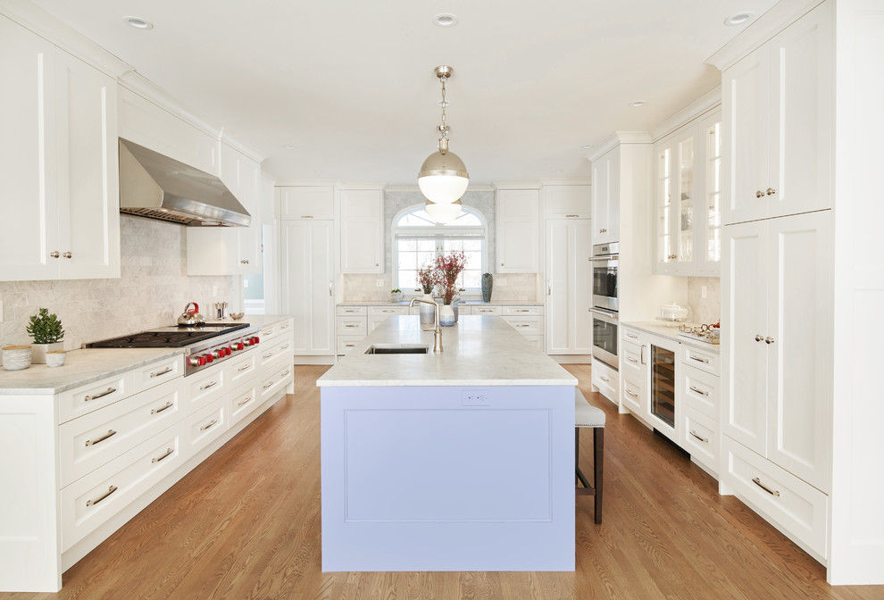 This is an example of a large transitional separate kitchen in Minneapolis with an undermount sink, flat-panel cabinets, white cabinets, marble benchtops, white splashback, subway tile splashback, stainless steel appliances, medium hardwood floors, with island and brown floor.