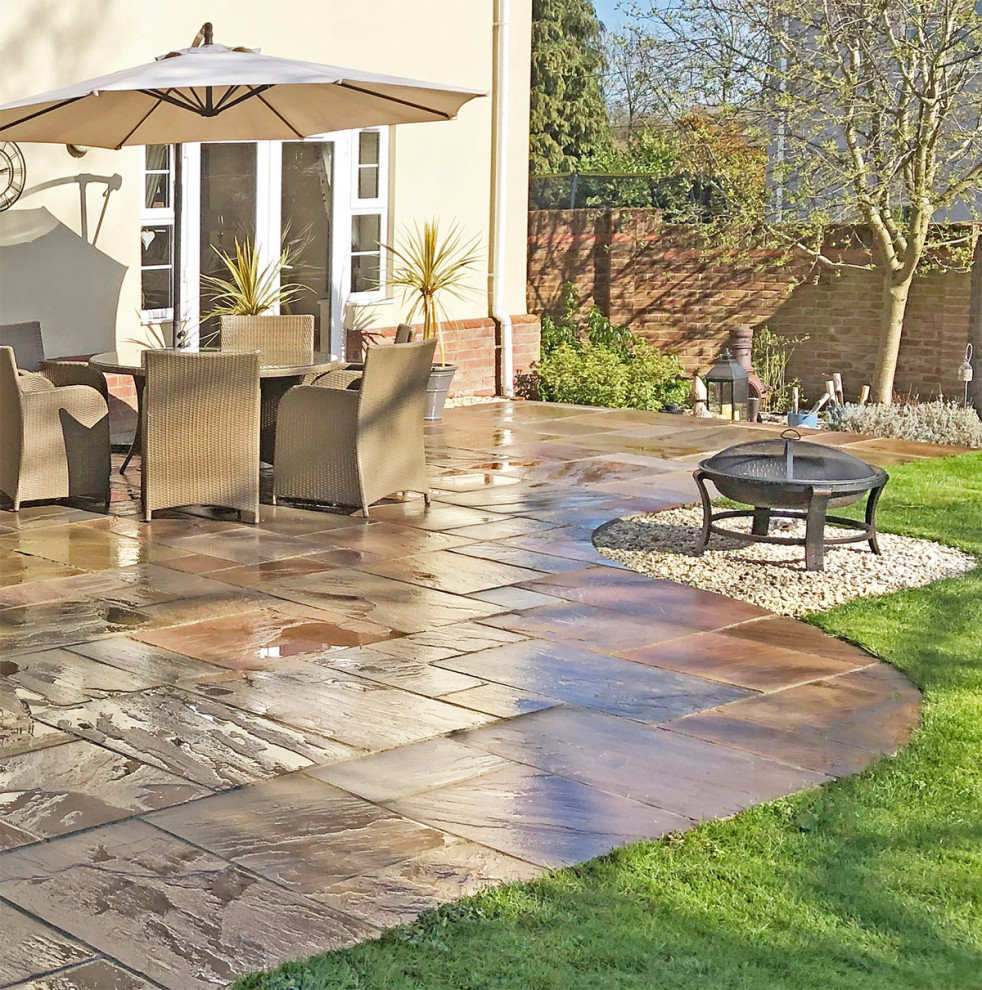 Design ideas for a medium sized traditional back patio in Hertfordshire with natural stone paving.
