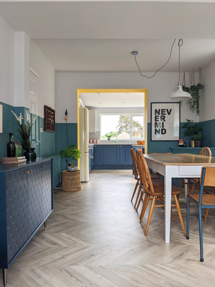 This is an example of a large beach style l-shaped open plan kitchen in Other with an integrated sink, shaker cabinets, blue cabinets, laminate benchtops, grey splashback, ceramic splashback, black appliances, laminate floors, with island and grey benchtop.