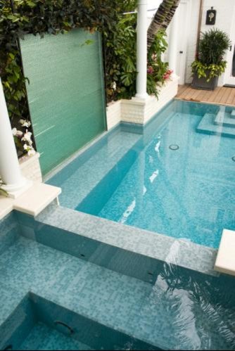 Design ideas for a small beach style courtyard rectangular infinity pool in Los Angeles with a water feature and decking.
