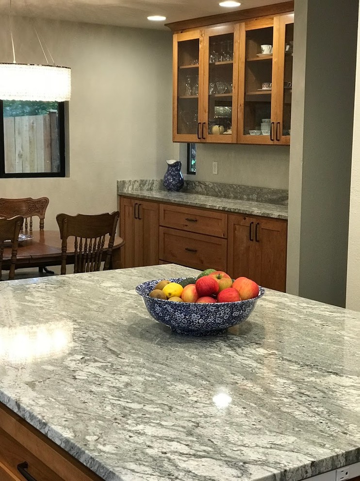 Example of a mid-sized transitional l-shaped dark wood floor and brown floor eat-in kitchen design in Seattle with a farmhouse sink, shaker cabinets, medium tone wood cabinets, granite countertops, stainless steel appliances, an island and gray countertops