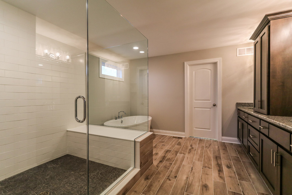 Inspiration for a mid-sized contemporary master white tile and subway tile vinyl floor and brown floor freestanding bathtub remodel in Chicago with shaker cabinets, light wood cabinets, beige walls, granite countertops and a hinged shower door