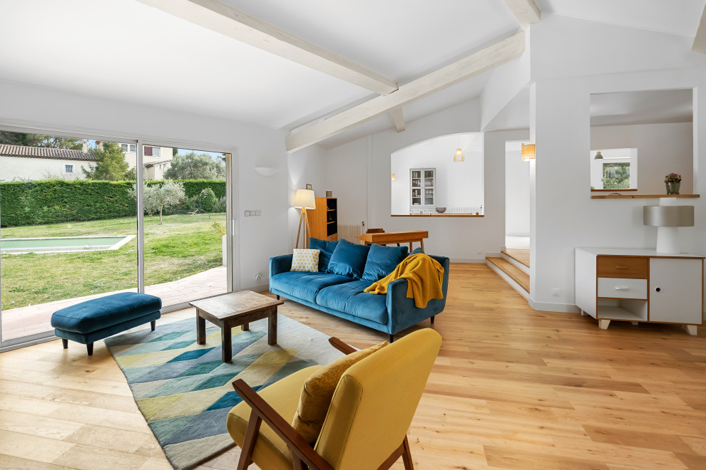 Cette photo montre un grand salon ouvert avec un mur bleu, parquet clair, un poêle à bois, un téléviseur fixé au mur, un sol beige, poutres apparentes et un plafond cathédrale.