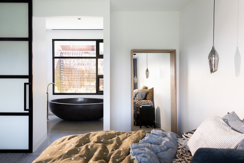 This is an example of an industrial bedroom in Melbourne with white walls, concrete floors and grey floor.