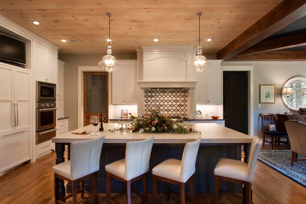 Mid-sized transitional l-shaped medium tone wood floor and brown floor eat-in kitchen photo with an undermount sink, shaker cabinets, blue cabinets, quartzite countertops, multicolored backsplash, glass tile backsplash, stainless steel appliances, an island and white countertops