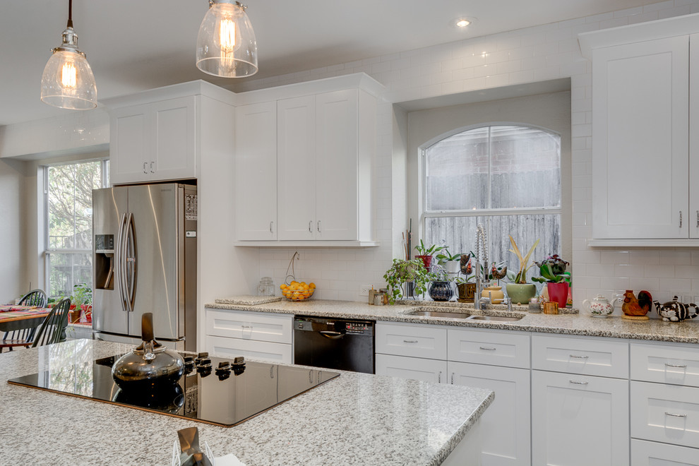 Mid-sized transitional l-shaped eat-in kitchen in Dallas with an undermount sink, shaker cabinets, white cabinets, granite benchtops, white splashback, subway tile splashback, stainless steel appliances, porcelain floors and with island.