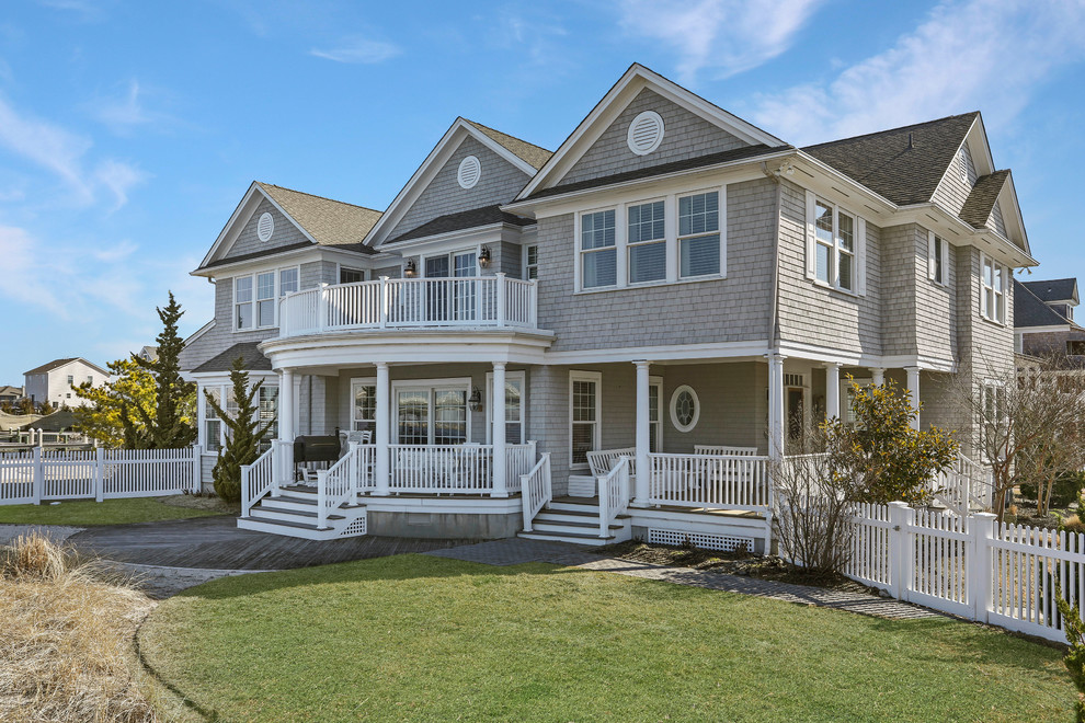 Photo of a large beach style two-storey grey house exterior in New York with wood siding, a gable roof and a shingle roof.
