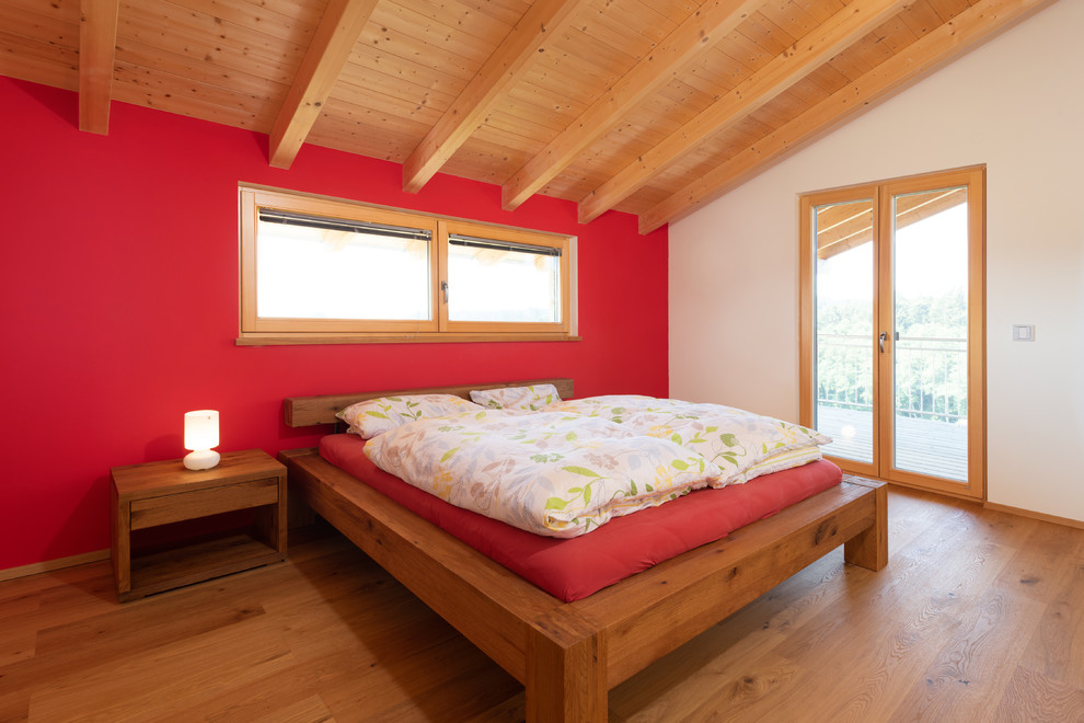 Großes Modernes Hauptschlafzimmer ohne Kamin mit roter Wandfarbe, braunem Holzboden und braunem Boden in Nürnberg