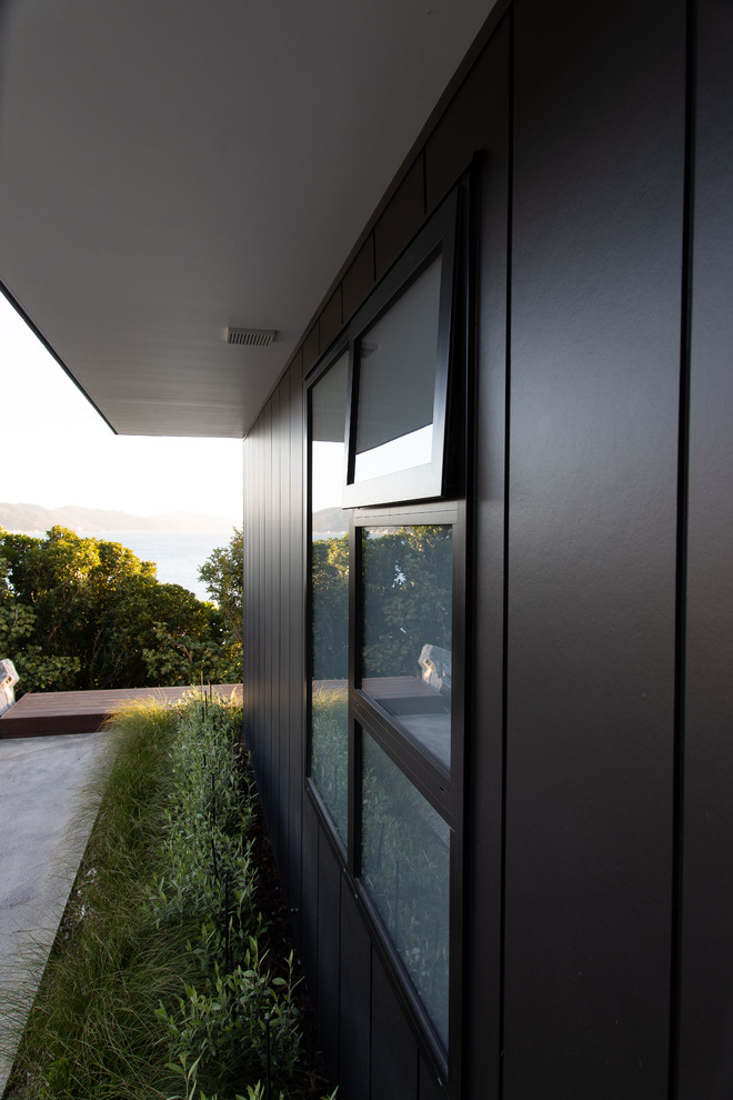 Inspiration for a large contemporary two-storey black house exterior in Wellington with wood siding.